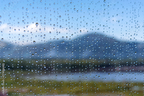 Raindrops on the window with a view of the mountain landscape.