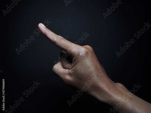 Male hand pointing isolated on black background. Body part gesture