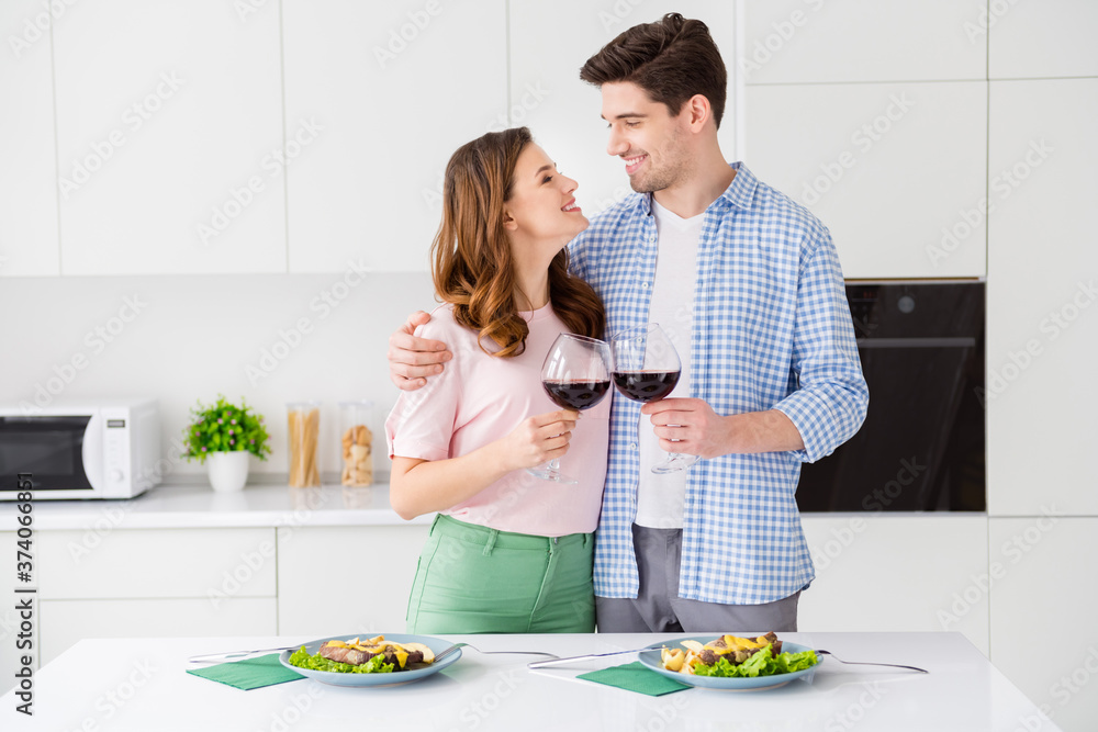 Portrait of his he her she two nice cheerful cheery affectionate people spending romance day eating tasty food domestic restaurant drinking red wine in light white interior kitchen house apartment