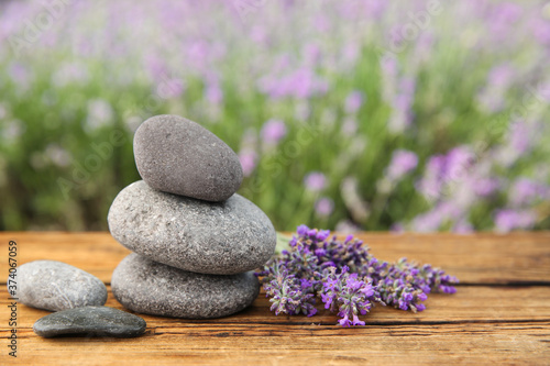 Spa stones and fresh lavender flowers on wooden table outdoors  closeup. Space for text