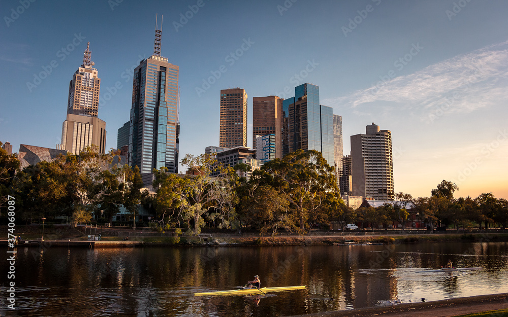 Fototapeta premium Cityscape and skyline of Melbourne. Man exercising in the city. A river in an urban environment with beautiful colors. 