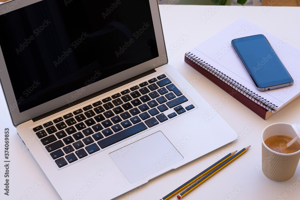 Outdoor work station on a white table, laptop, coffee cup, accessories and mobile phone - concept of relaxed work tech and social Outdoor work station on a white table, laptop, coffee cup, accessories and mobile phone - concept of relaxed work tech and social