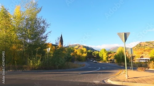 Slow motion pov point of view driving on Castle Creek road with sign to Maroon Creek road and Aspen chapel in mountain ski resort city small village in autumn with colorful foliage on trees