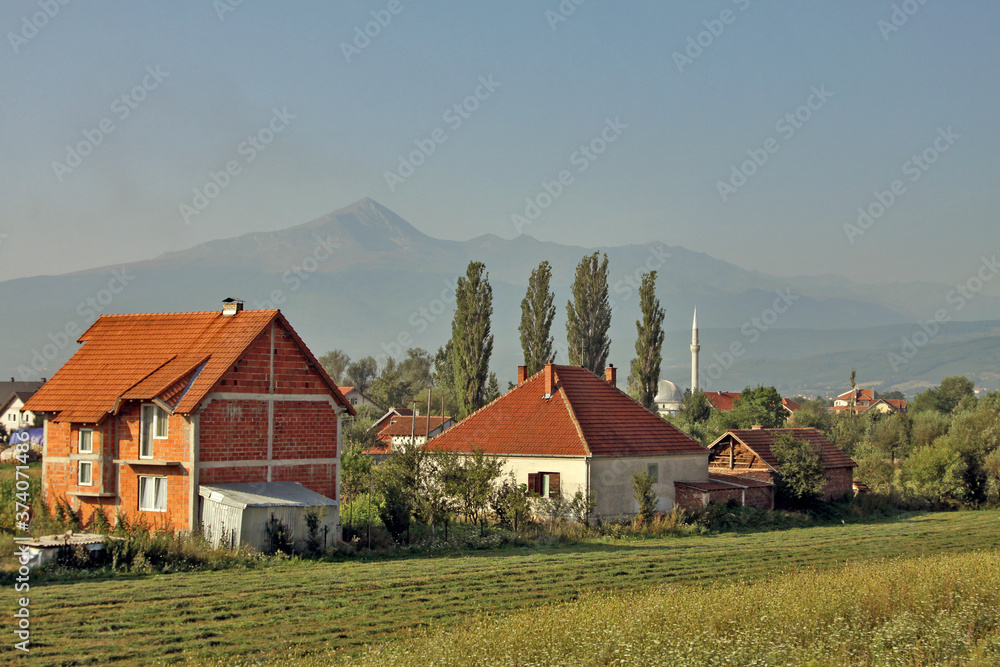 Kosovo - Ferizaj / Urosevac - The typical rural countryside landscape in the southern part of partially recognized state Kosovo with peasant brick houses and hazed Sar mountains in the background