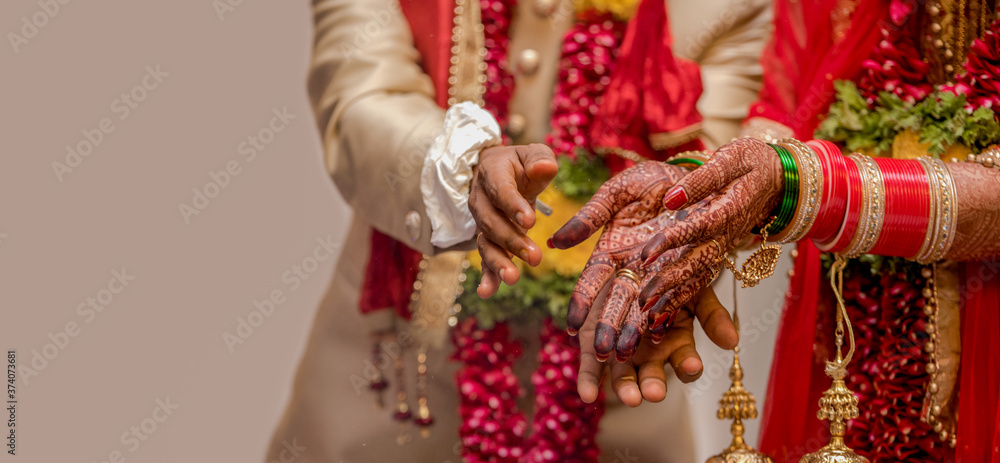 Very beautiful photo of a newly married Indian couple in ethnic attire offering flowers to God and taking blessings. Bride hands are decorated with henna design and colorful nuptial bangles. - Image.