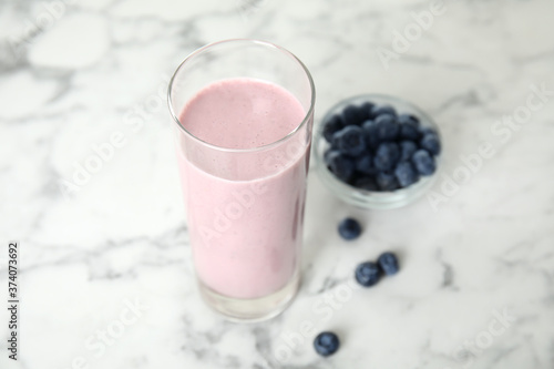Tasty milk shake and blueberries on white marble table