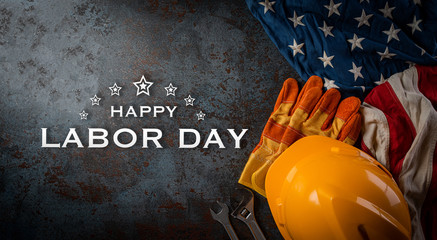 Happy Labor day concept. American flag with different construction tools on dark stone background, with copy space for text.