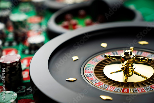 Casino theme, close up of roulette, red and black numbers. Stack of chips in the background. © zolnierek