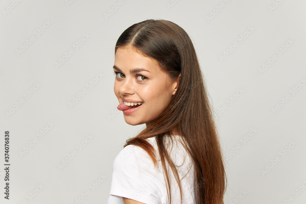 Happy woman sticks out tongue and looks back in t-shirt