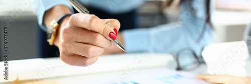 Woman in office holds a pen in her hand over chart. Business analytics concept