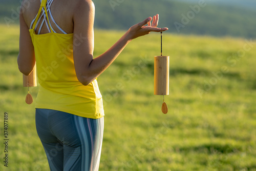 Bild auf Leinwand Attractive Caucasian woman holding Koshi chimes musical instruments in her hands, enjoying the healing and relaxing sounds of the bells on a sunny morning in the heart of nature