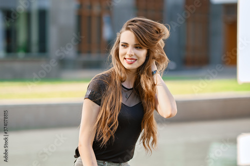 Positive young woman with long curly hair outdoor