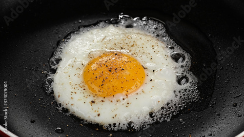 frying egg with seasoning in pan top view