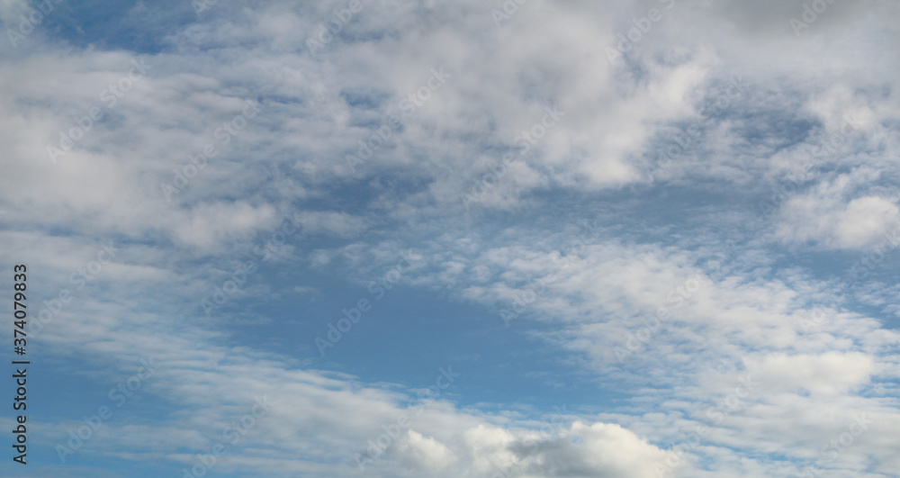 Blue bright sky with clouds, natural beautiful background. Soft daylight. Stock photo with empty space for text and design. 
