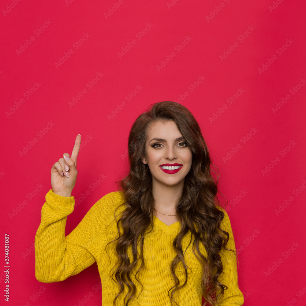 Smiling Young Woman In Yellow Sweater Is Pointing Up Smiling Young Woman In Yellow Sweater Is Pointing Up