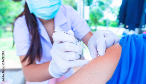 Female doctor wearing a white coat is inject vaccine to prevent disease for people.