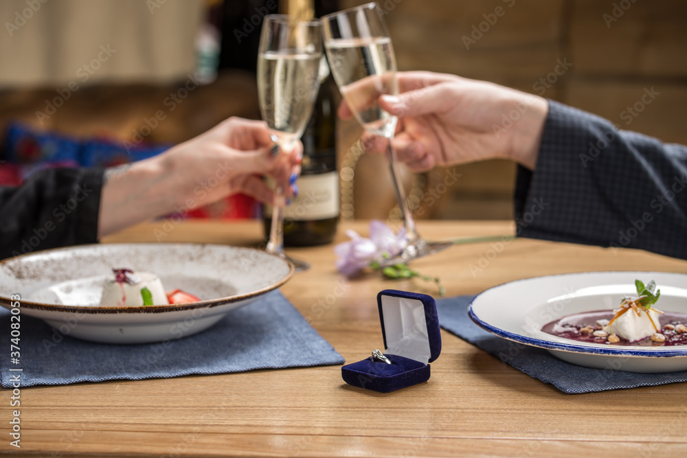 marriage proposal with ring on the table at restaurant couple holding champagne glasses marriage proposal with ring on the table at restaurant couple holding champagne glasses