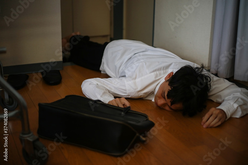 飲みすぎて玄関で寝る男性 © yamasan
