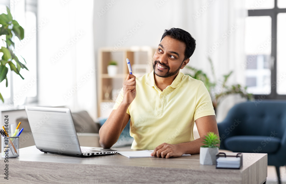remote job, idea and people concept - happy smiling young indian man with notebook and laptop computer at home office