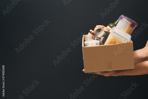 A young man volunteer is holding a donation box with foodstuffs. photo