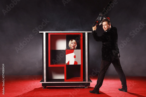 Magician man show trick with box illusion his is saws the girl a chainsaw on the ring in circus