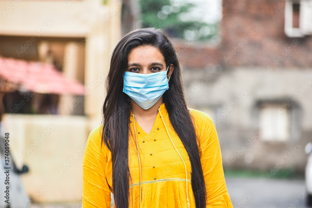 Fototapeta premium Portrait of Indian girl in mask staring at camera.