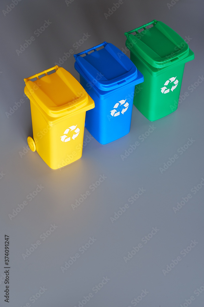 Three color coded recycle bins, isometric picture on geometric paper  background with copy-space. Recycling sign on the bins, blue, yellow and  green. Waste separation to recycle plastic and glass. Stock Photo |