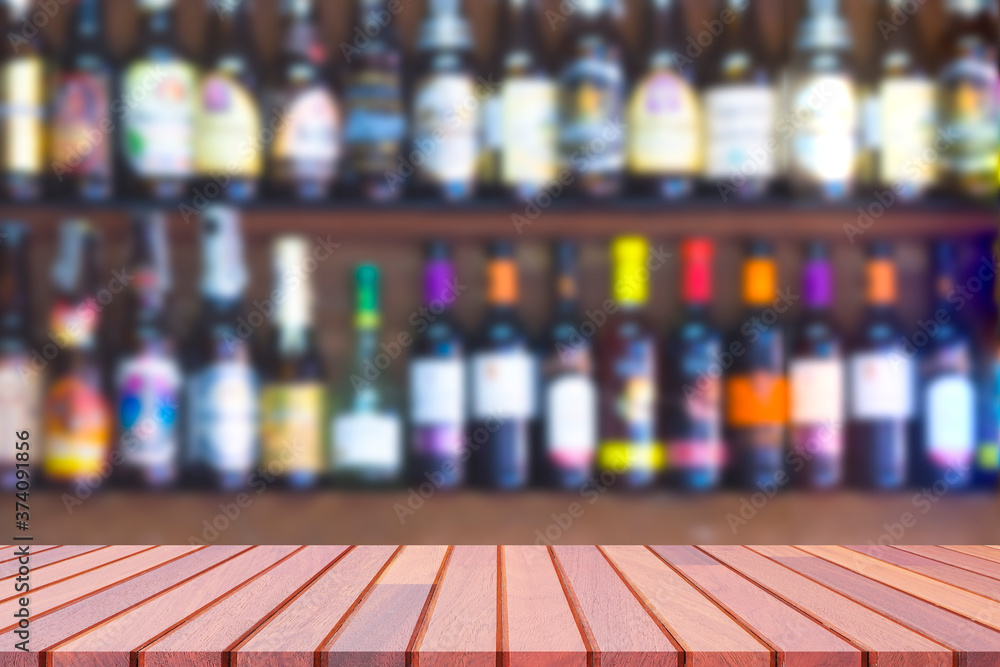 Empty wooden counter with blurred background of many liquor and brandy on shelf of wooden wall decoration in vintage liquor store