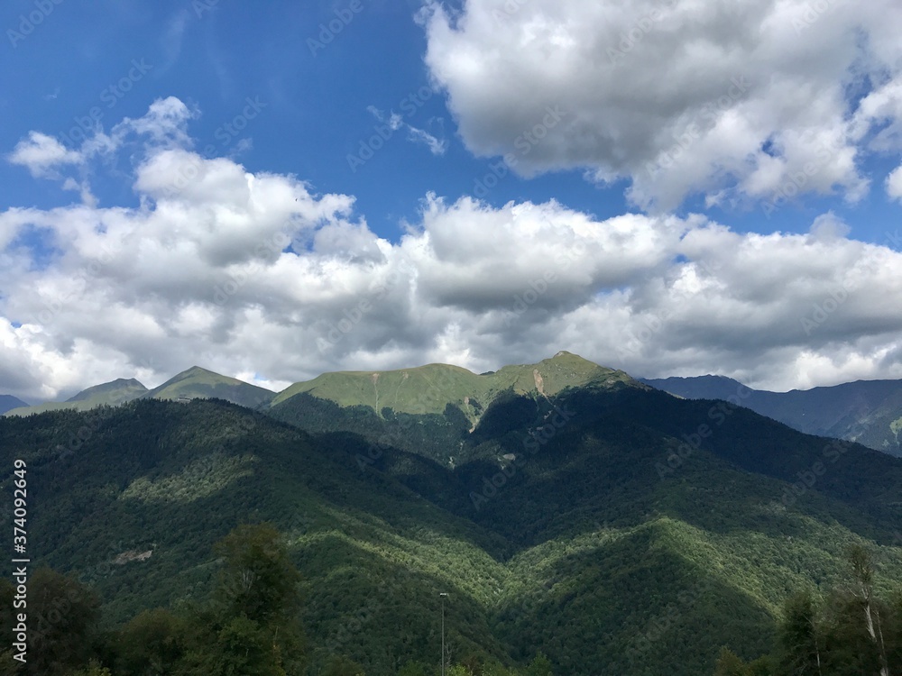 Mountain green landscape with white clouds on blue sky. Nature wallpaper