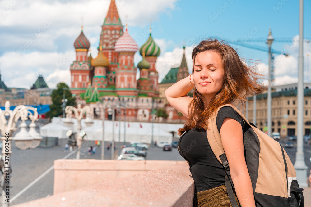 A charming young woman stands on a bridge with a background on the Kremlin in Moscow, Russia's main attraction