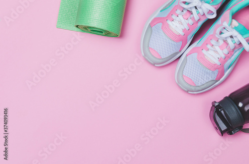 Yoga mat, sport shoes, bottle of water on pink background. Healthy lifestyle