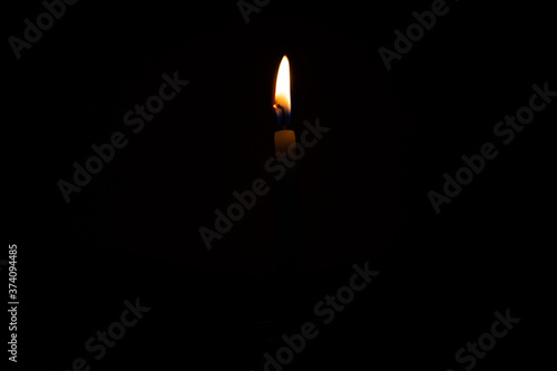 Close Up Single Burning, Bright White Paraffin Candle Light On Isolated Dark Black Background. Red, orange, yellow candle fire flame smoke in party festival celebration at night. Copy Space For Text.