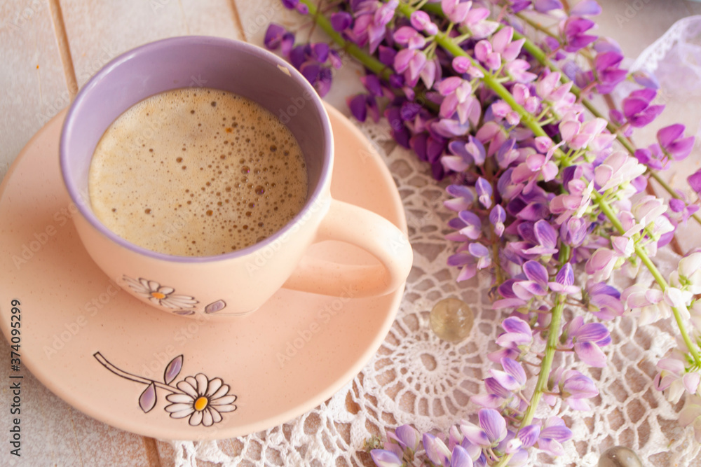 Morning scene with a cup of coffee surrounded by purple wild flowers of lupine Morning scene with a cup of coffee surrounded by purple wild flowers of lupine