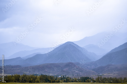 Misty landscape of high blue mountains. Green forest under the mountains.
