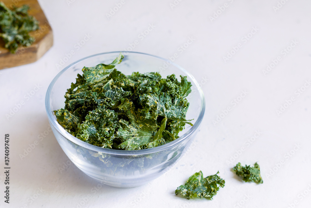 Kale chips in a glass bowl on a white background. copy space