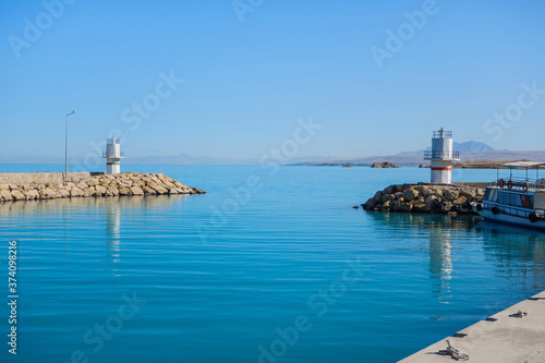 Lighthouses at end of dam that surrounding bay of tourist boats, Van Lake, Gevaş, Turkey. Bright blue colour of water is created by saline soda elements in its consist