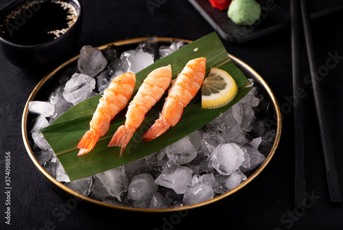 shrimp sashimi on ice in a black plate