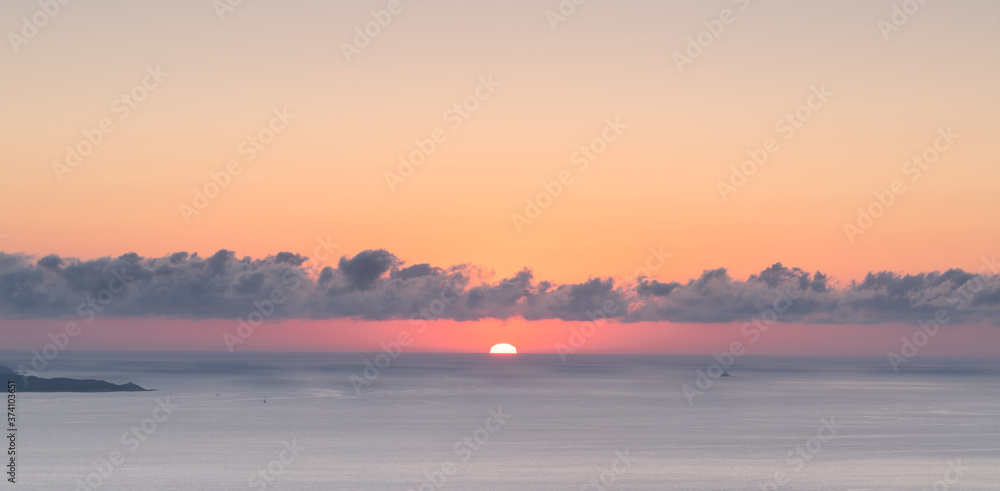 Puffy clouds and setting sun over the Mediterranean island of Corsica