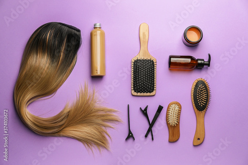 Unusual wig with hairdresser supplies on color background photo