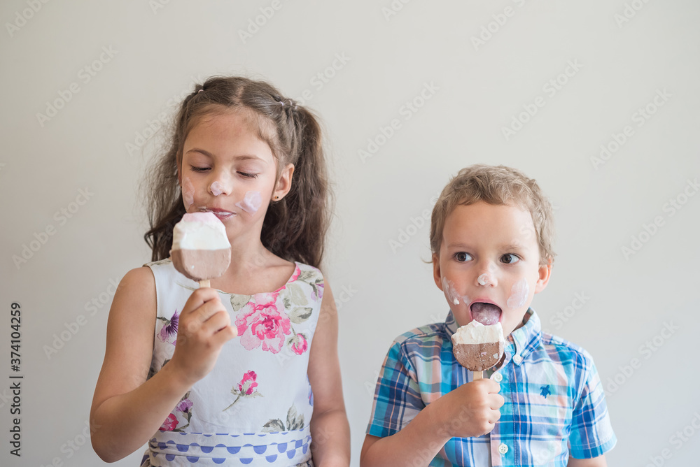 Beautiful children stained their cheeks and nose with ice cream. Two stylish children with ice cream in their hands