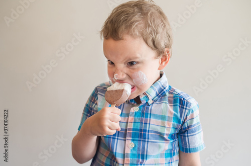 Beautiful baby eats ice cream and writhes grimace from a cold dessert. Sweet Summer Dessert