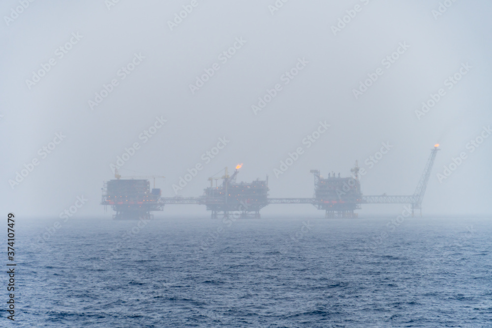 Misty morning at oil filed with a oil production platform complex in the background Misty morning at oil filed with a oil production platform complex in the background