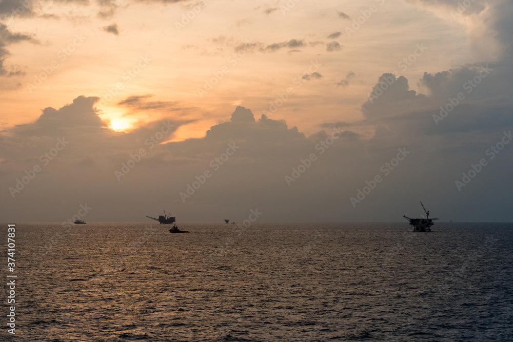 Supply boat and diving vessel steaming at an oil field during sunrise