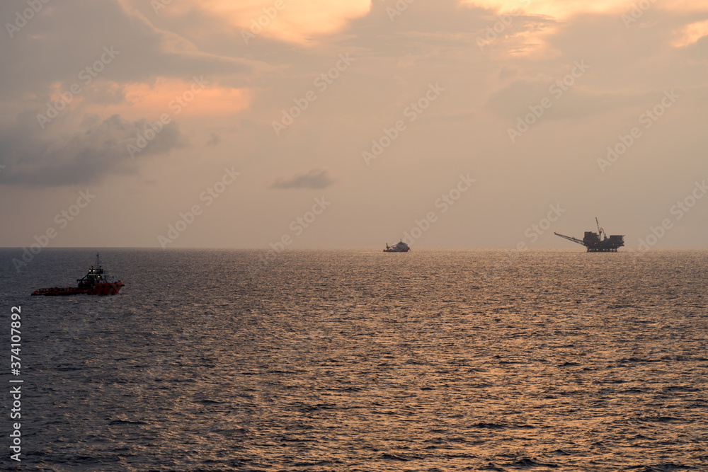 Supply boat and diving vessel steaming at an oil field during sunrise