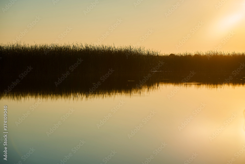 Landscape of a beautiful sunset on the river with sun and sky glare