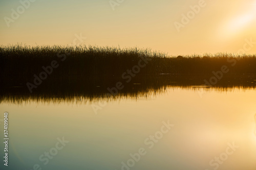 Landscape of a beautiful sunset on the river with sun and sky glare