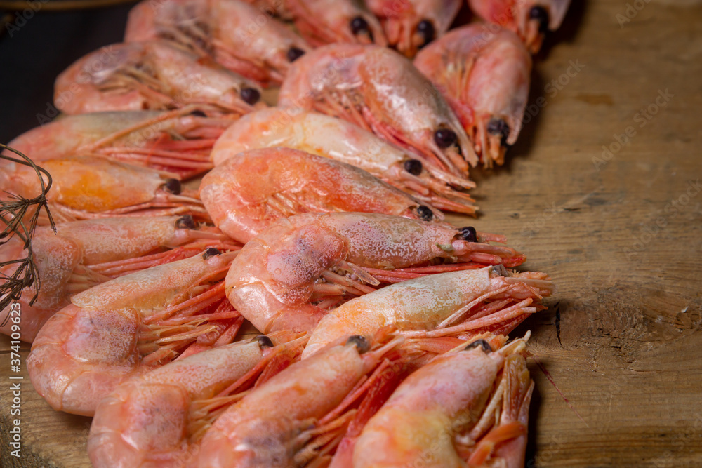 Boiled shrimp. Shrimps lie on a wooden board. Decorated around with dry greenery. Seafood Boiled shrimp. Shrimps lie on a wooden board. Decorated around with dry greenery. Seafood