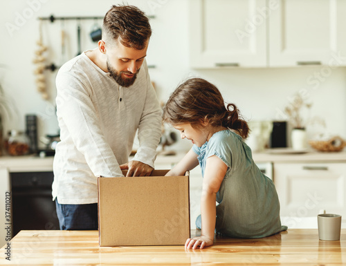 Father and kid unpacking carton box at home.