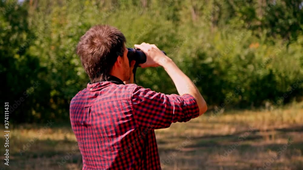 Man looking through binocular at the forest. Bird watching. Nature explore. Hiking tourist. Man looking through binocular at the forest. Bird watching. Nature explore. Hiking tourist.