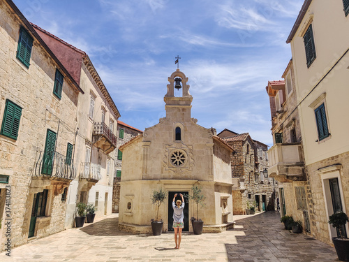 Female tourist taking photo of mall church on square of small urban village of Stari grad on Hvar island in Croatia, Adriatic Sea, Europe. photo